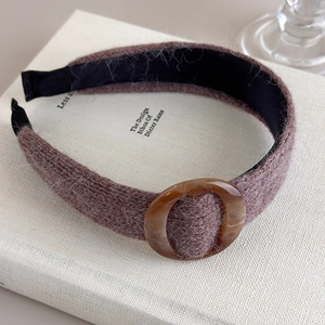 Gros plan d'un bandeau en maille marron avec boucle en résine ambrée sur des livres