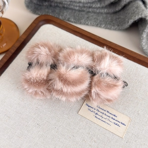 Détail macro d'une pince à cheveux en fausse fourrure avec pompons rose brun moelleux
