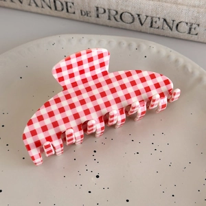 Close-up of red and white gingham acetate hair claw clip on a vintage ceramic plate