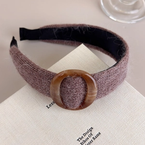 Gros plan du bandeau tricoté marron avec boucle en résine sur un livre blanc