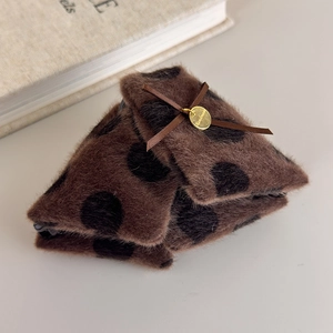 Detailed macro of brown plush hair claw clip with black polka dots and golden handmade charm