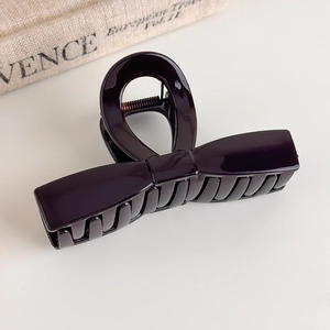 Close-up of a glossy chocolate brown bow claw clip with a sleek metallic finish