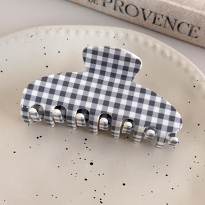 Detail of large acetate hair claw clip featuring classic black and white gingham pattern