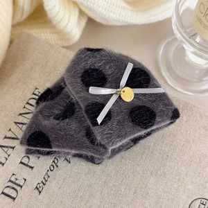 Detail of soft plush polka dot accessory with satin bow and golden handmade charm