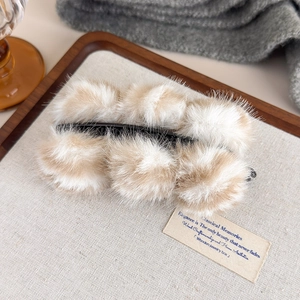 Détail macro d'une pince banane en peluche avec pompons doux à imprimé léopard beige