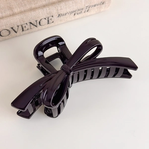 Macro detail of glossy chocolate brown bow hair claw clip showing smooth resin texture