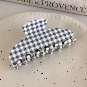 Blue and white gingham checkered acetate hair claw clip displayed on a ceramic dish