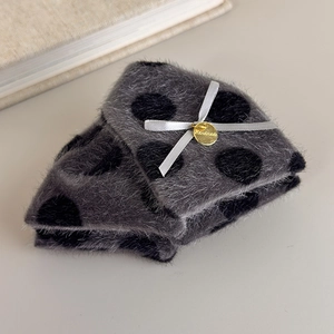 Close-up of plush grey polka dot shark clip with handmade charm and ribbon bow