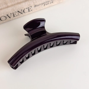 Detail view of large glossy dark purple resin hair claw clip on a stylish magazine