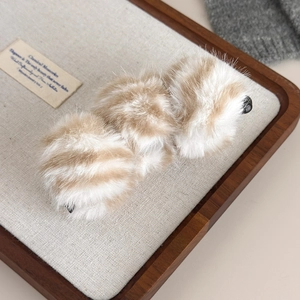 Détail d'une pince banane en peluche léopard sur un plateau en bois pour coiffure d'automne