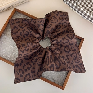 Detailed view of brown leopard print scrunchie on glass tray with matte fabric texture