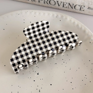 Detailed view of a large black and white checkered acetate hair claw clip on a ceramic tray