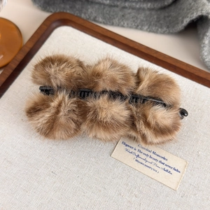 Détail d'une pince à cheveux banane en peluche léopard sur un tissu doux élégant
