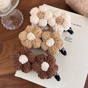 Close-up of three knitted wool flower hair clips in beige, khaki and coffee colors