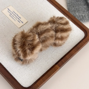 Détail de trois boules en fausse fourrure léopard sur une pince à cheveux banane