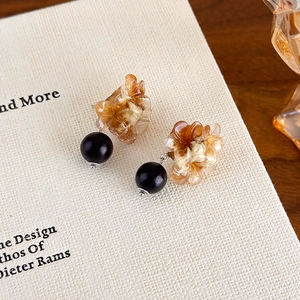 Detail view of amber resin flower earrings with black matte beads on white book