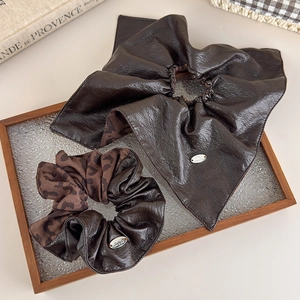 Detail of brown leather and leopard print scrunchies on a glass tray for women