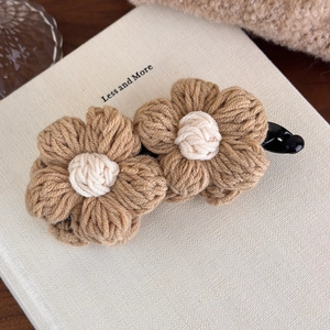 Close-up of handmade knit flower hair clip in vintage brown and cream white tones