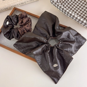 Close-up of leopard print and brown faux leather scrunchies on a glass tray