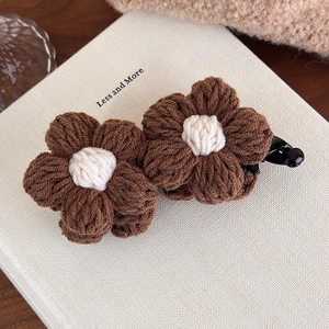 Detail of handmade crocheted brown flower hair clip with cream center on black base