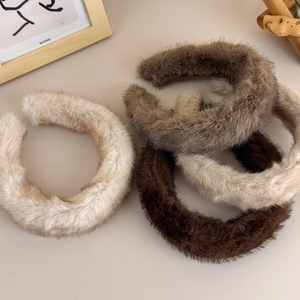 Vue à plat de plusieurs serre-têtes en peluche aux tons neutres en fausse fourrure