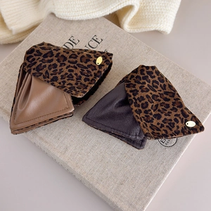 Macro shot of triangle leopard print faux fur hair claw clip on vintage beige book