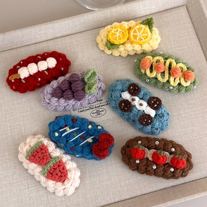Detailed view of eight handmade crochet fruit hair clips with delicate knit patterns