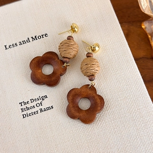 Detail of vintage geometric earrings with wood flower and woven ball texture