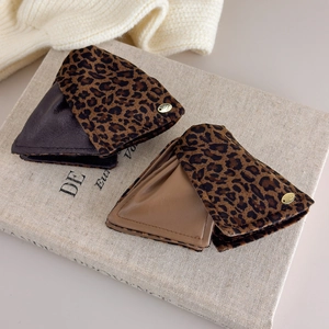 Close-up of leopard print triangle hair clips with gold logo on vintage book background