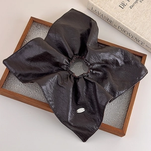 Detail of coffee brown leather scrunchie with silver plaque and vintage decor