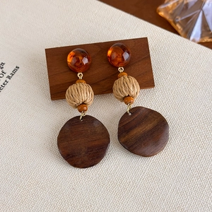 Macro detail of retro wooden earrings featuring amber resin and woven rope textures