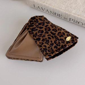 Detail view of leopard faux fur ear muffs with brown leather lining and gold logo