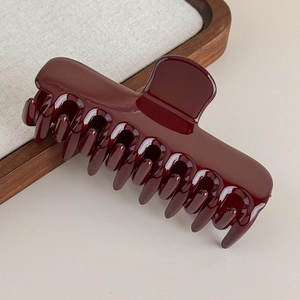 Détail d'une grande pince à cheveux bordeaux brillante avec ressort métallique solide