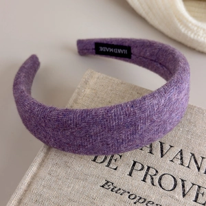 Detailaufnahme der dunkelvioletten gepolsterten Woll-Stirnbands mit handgemachtem Label