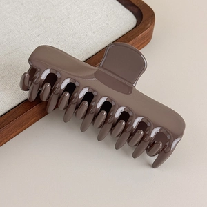 Détail de la grande pince à cheveux marron moka au fini résine brillante sur plateau