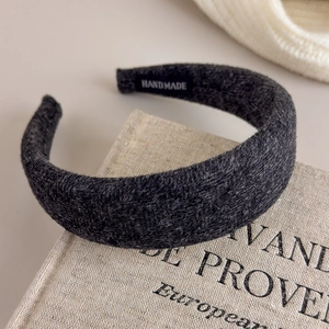 Detail eines handgefertigten breiten Wollstirnbandes mit weicher Textur und Etikett