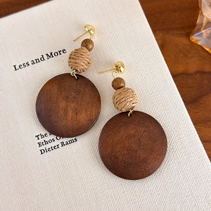 Detail of vintage geometric wood and woven earrings on a book background