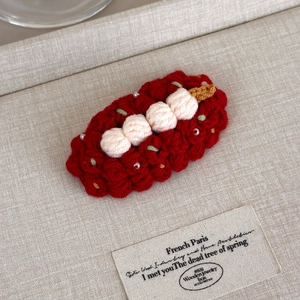 Macro view of handmade red crochet fruit hair clip with intricate yarn texture