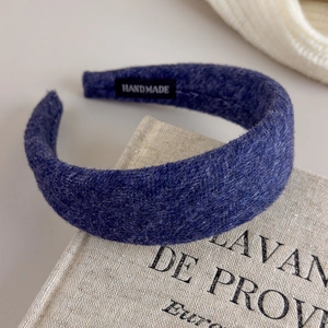 Detail eines dunkelblauen Woll-Stirnbands mit handgefertigtem Label auf Leinenbuch