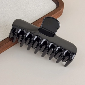 Détail d'une grande pince à cheveux noir brillant avec ressort métallique robuste