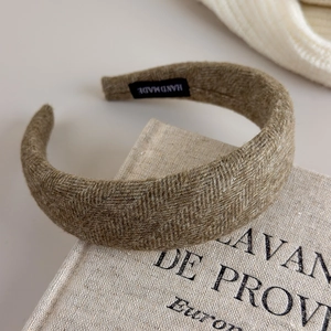 Detailansicht des braunen Fischgräten-Wollstirnbands mit einem Handmade-Etikett