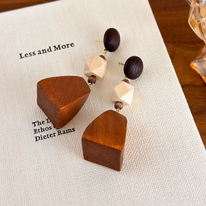 Detail view of geometric wooden earrings with walnut brown and cream elements