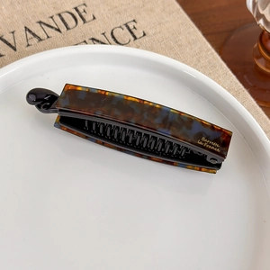 Detailansicht der Acetat-Bananenspange mit Schildpattmuster und goldener Aufschrift im Detail