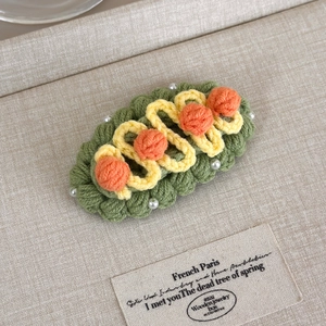 Detail of handmade crochet hair clip featuring green wool knit and pearl embellishments