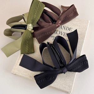 Three large knit bow banana clips in olive, brown, and black for thick hair styling