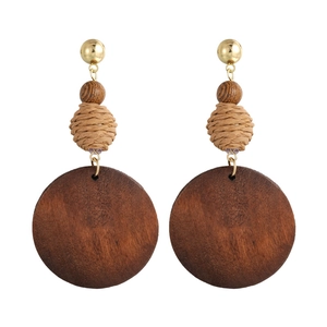Detailed view of bohemian vintage wooden earrings with woven raffia beads and metal studs
