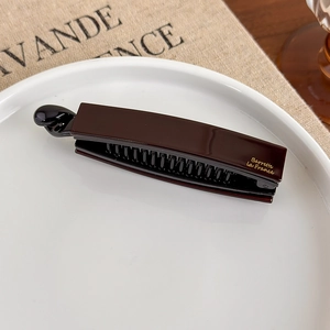 Makro-Detail der dunkelbraunen Bananen-Haarklammer mit goldenem Barrette La France-Schriftzug