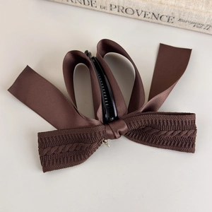 Detail of vintage brown knit and satin bow banana hair clip with elegant metal buckle