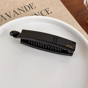 Detailansicht der schwarzen Acetat-Bananenspange mit goldener Barrette La France Aufschrift