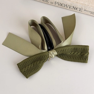 Detailed view of the layered knit and satin bow banana clip with elegant cable patterns
